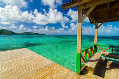 Pier by turquoise sea against sky