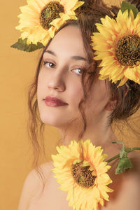 Close-up portrait of woman against sunflower