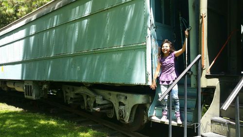 Full length of cheerful girl standing in train