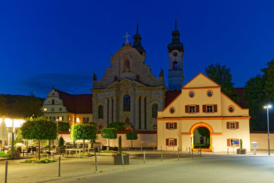 Illuminated building against blue sky at night