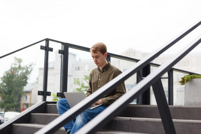 Man working on laptop sitting on the stairs of business center