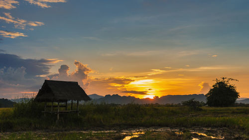 House on field against sky during sunset