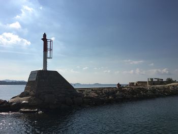 Lighthouse by sea against sky