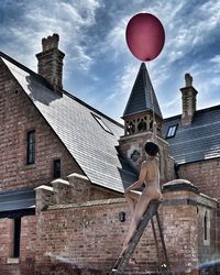 Low angle view of balloons on building against sky