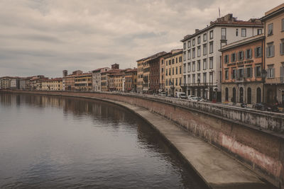 Bridge over river by buildings against sky in city