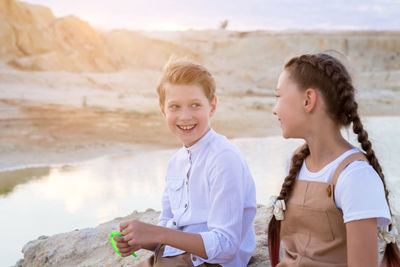 Friends a boy and a girl are sitting rock in the mountains before launching a kite.