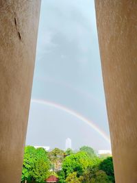 Low angle view of rainbow over building against sky
