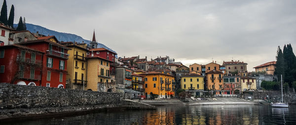 Buildings by river in town against sky