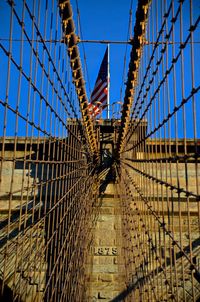 American flag on brooklyn bridge against blue sky