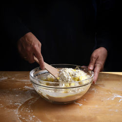 Cropped hands mixing batter in bowl on table