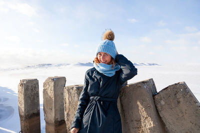 Close up portrait of beauty woman in frosty stylish coat around frozen sea and stone 