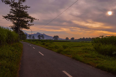 Road by land against sky during sunset