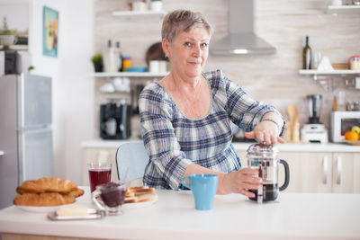 Senior woman making coffee at home