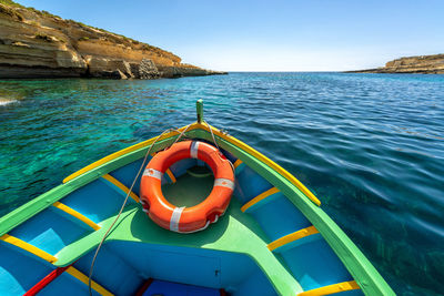 Rowboat sailing in sea against clear blue sky