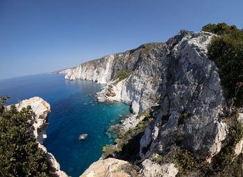 Scenic view of sea and mountains against clear blue sky
