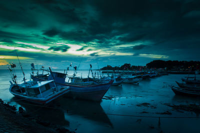 Boats moored in calm sea against cloudy sky