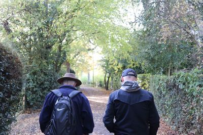 Rear view of man walking on street amidst trees