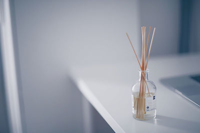 Close-up of glass container on table against wall