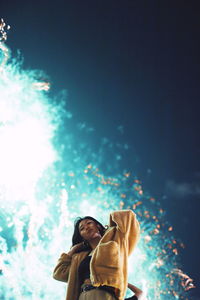 Low angle view of woman standing by tree against sky