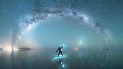 Rear view of man standing against star field in sky at night