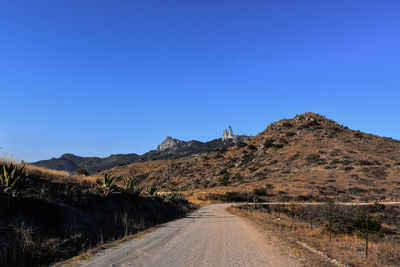 Road by mountain against clear blue sky