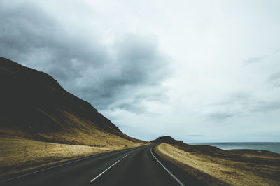 Road by mountain against sky