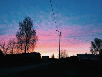 Low angle view of silhouette electricity pylon against sky at sunset