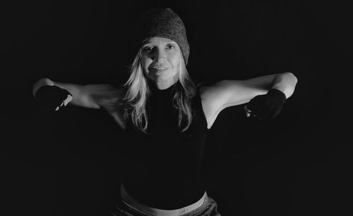 Portrait of woman flexing muscles against black background