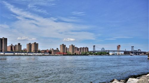 Sea by buildings in city against sky