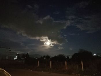 Silhouette landscape against cloudy sky at night