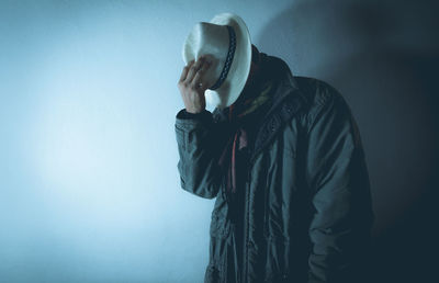 Man wearing hat while standing against wall