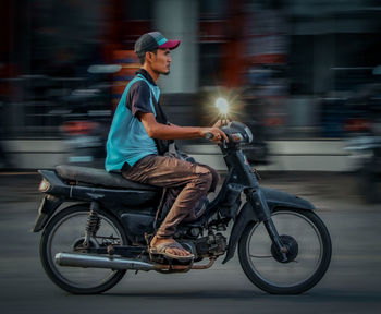 Side view of man riding motorcycle on road