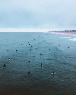 High angle view of people surfing in sea against sky