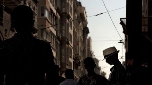 Rear view of silhouette people walking on street amidst buildings