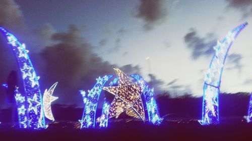 Low angle view of illuminated christmas lights against sky at night