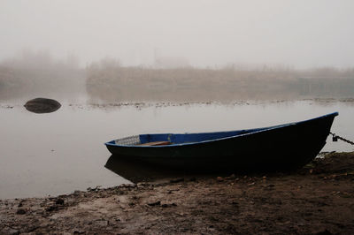 Boat moored on shore against sky