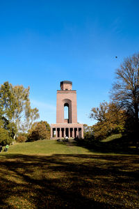 Built structure on field against clear blue sky