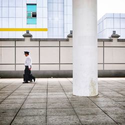 Man walking on footpath against building