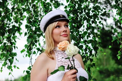 Portrait of beautiful young woman standing against plants