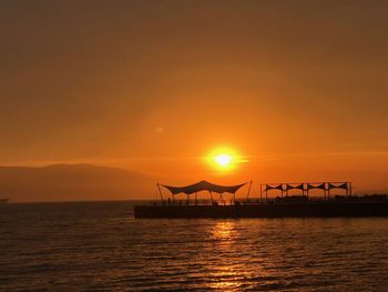 Silhouette pier over sea against sky during sunset