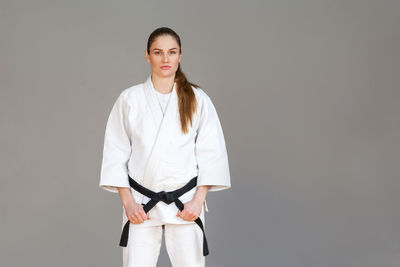 Portrait of woman standing against gray background