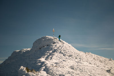 Low angle view of people on snow covered mountain against sky