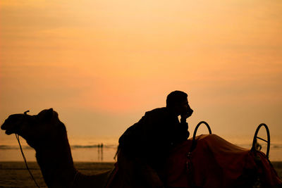 Silhouette person standing by orange sky during sunset