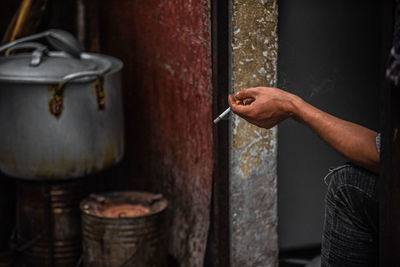 Midsection of man holding cigarette in container