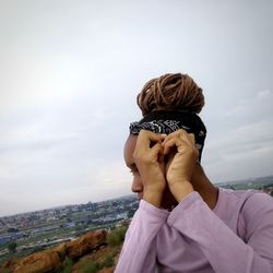 Rear view of woman looking at cityscape against sky