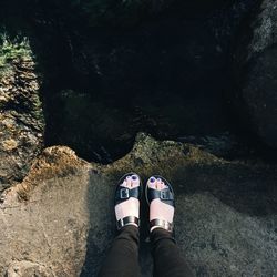 Low section of woman standing on rock by sea