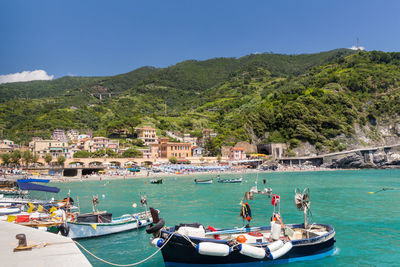 Boats in sea by mountains against clear sky