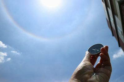 Low angle view of person holding umbrella against sky