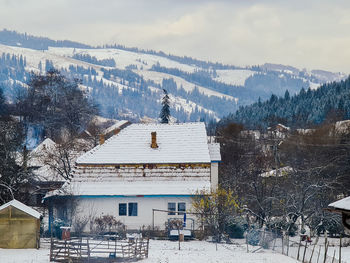 Snow covered houses and trees against sky