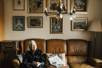 Senior woman contemplating sitting on sofa in living room at home